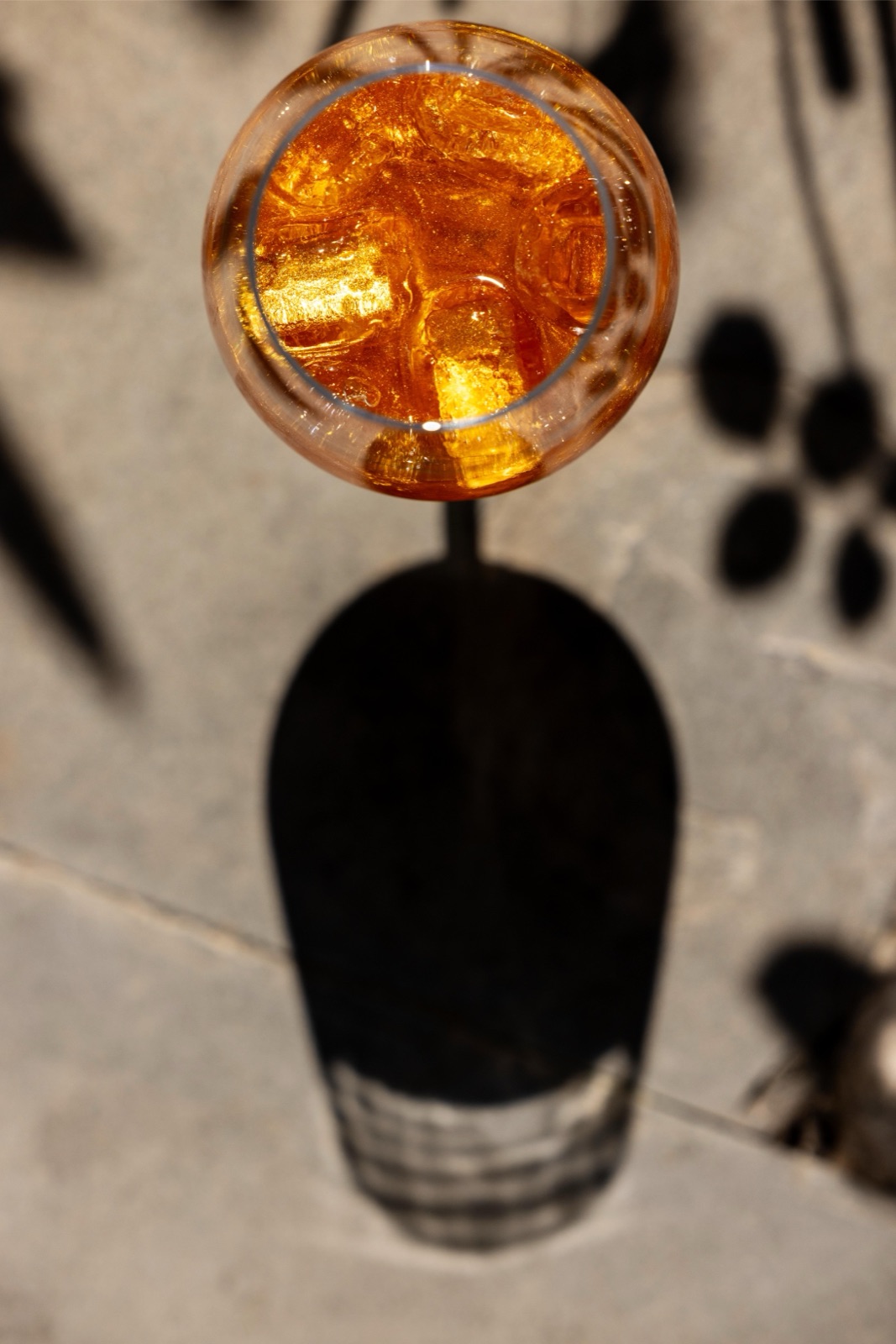 A spritz seen from above, casting a long shadow on stone